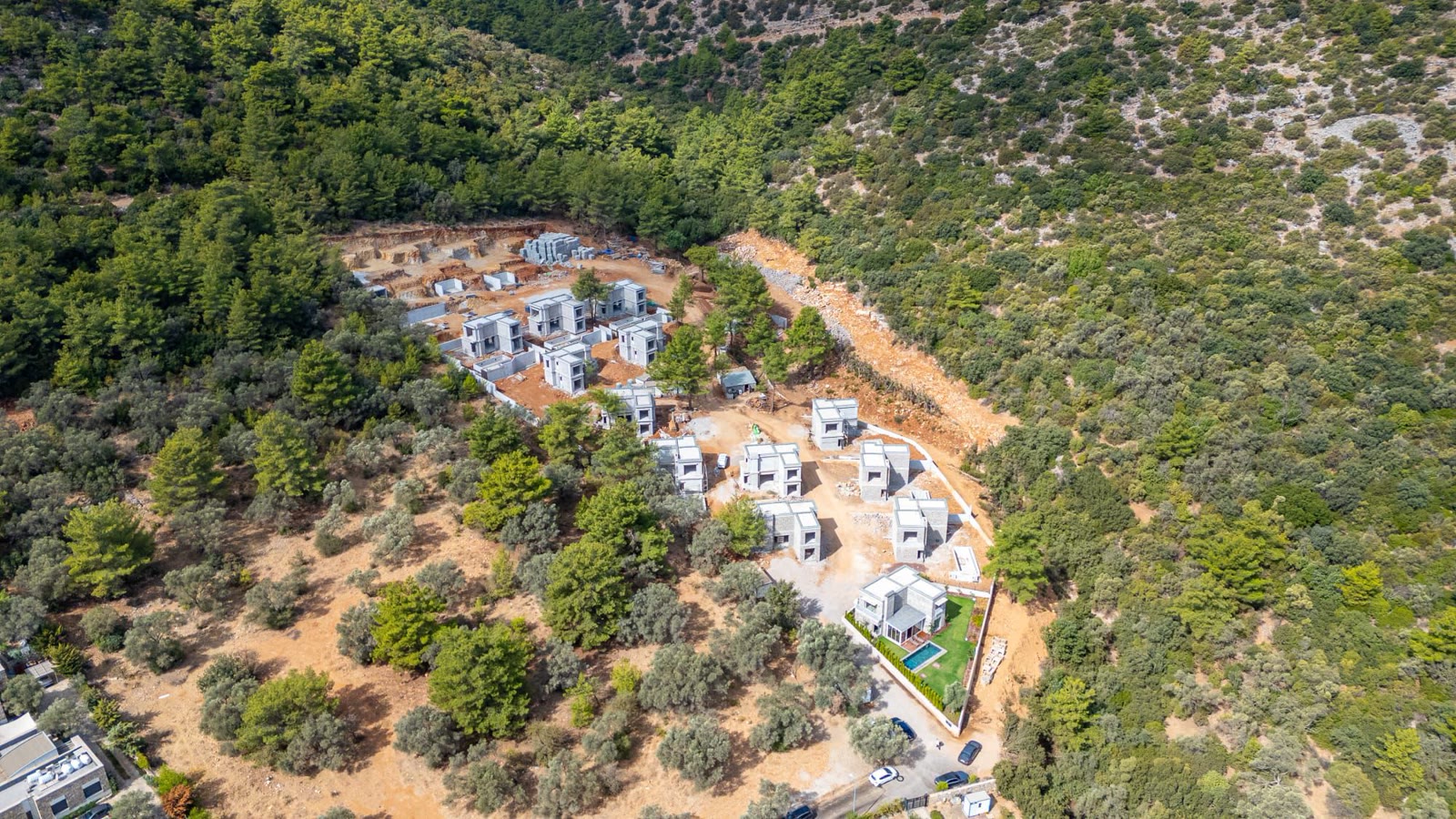Sahanın drone ile çekilmiş gerçek hali: kaba inşaat halindeki villalar, toprak zemin.